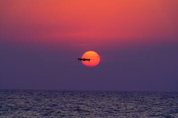 美しい海と夕陽に重なるドローン