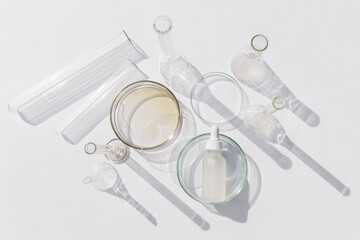 Top view of laboratory glassware and cosmetic glass bottle on grey background. Natural medicine, cosmetic research, bio science, organic skin care products.