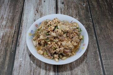 Traditional spicy salad of chopped chicken meat with shallot, coriander, chilly, ground roasted rice and lime juice on the plate. Famous street food menu in local Thailand. 
