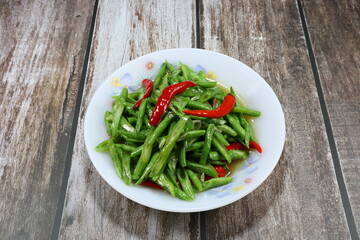 Traditional fried and stirred sliced green bean with fresh red chilly seasoning with pepper and soy sauce. Famous hot and spicy vegetarian menu in Thailand street food.