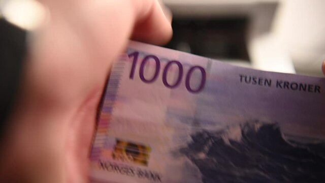 Close Up Of Caucasian Man Holding One Thousand Krone Bills In His Hand Counting And Putting Them In Neat Pile. 