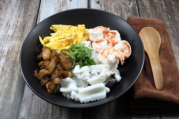 Traditional oriental and special porridge with boiled topping meat, boiled fresh peeled shrimp, chopped fried egg, steamed squid and roasted pork in the bowl. Famous street food breakfast menu.