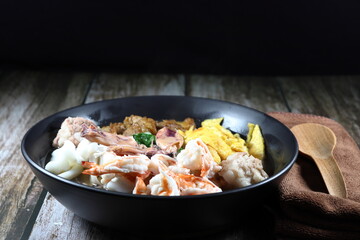 Traditional oriental and special porridge with boiled topping meat, boiled fresh peeled shrimp, chopped fried egg, steamed squid and roasted pork in the bowl. Famous street food breakfast menu.