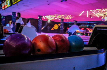 Bowling Balls inside a dark, neon lit bowling alley