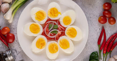 Half boiled egg in a white plate with tomatoes and spring onions.