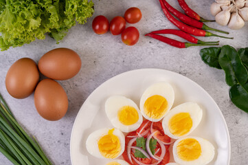 Half boiled egg in a white plate with tomatoes and spring onions.