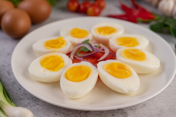 Half boiled egg in a white plate with tomatoes and spring onions.