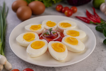 Half boiled egg in a white plate with tomatoes and spring onions.