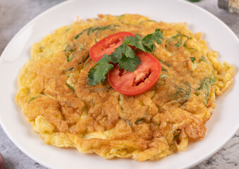 Omelet in a white plate garnished with tomatoes and coriander.