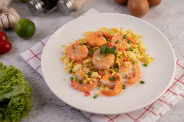 Stir fried eggs with shrimp on a white plate.