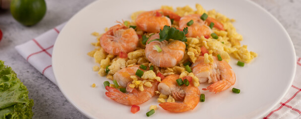 Stir fried eggs with shrimp on a white plate.