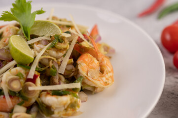 Shrimp cooked with lemongrass, vegetables, lime and chili on a white plate