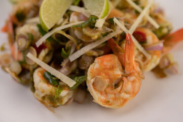 Shrimp cooked with lemongrass, vegetables, lime and chili on a white plate