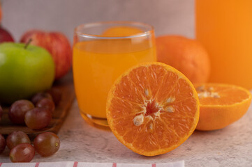 Orange cut in half with grapes and orange juice.