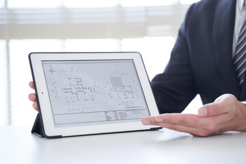 タブレットで一戸建ての物件を案内する日本人男性不動産営業マン