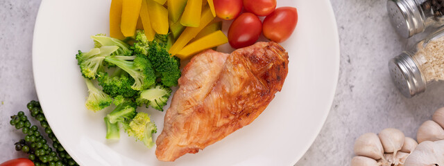 Chicken steak topped with white sesame, peas, tomatoes, broccoli and pumpkin in a white plate.