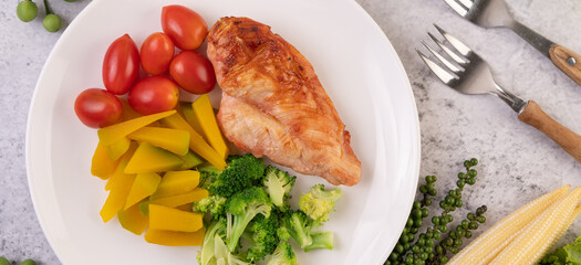 Chicken steak topped with white sesame, peas, tomatoes, broccoli and pumpkin in a white plate.
