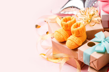 Pair of small yellow baby socks and gift box on pink background with gift present boxes and copy space for your warm message, baby shower, first newborn party background, banner