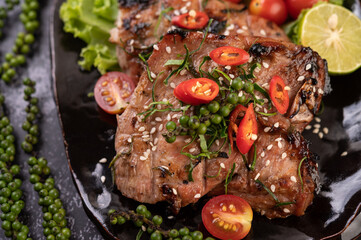 Sliced ​​pork steak topped with white sesame and fresh pepper seeds along.