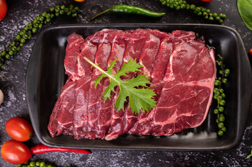 Sliced ​​raw pork used for cooking with chili, tomato, basil, and fresh pepper seeds.