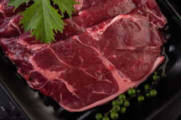 Sliced ​​raw pork used for cooking with chili, tomato, basil, and fresh pepper seeds.