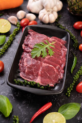 Sliced ​​raw pork used for cooking with chili, tomato, basil, and fresh pepper seeds.