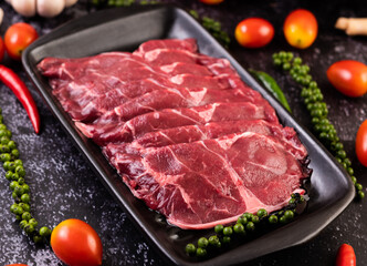 Sliced ​​raw pork used for cooking with chili, tomato, basil, and fresh pepper seeds.