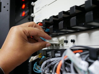 Technicians adjustment fiber optics cable network connected to internet switch servers in data...