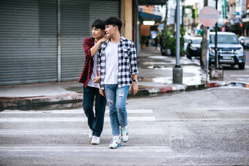 Two loving young men in shirts and walking on the street.