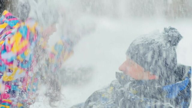 joyful little daughter throws fluffy snow spending time with mother and father in yard on winter day closeup slow motion