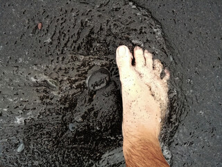 Bare Feet Walking on Black Sand and Sea Water