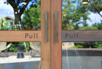 Fototapeta premium Glass door of restaurant with text pull on wood.