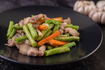 Stir-fried long beans and carrots, add pork belly, put on a black plate.