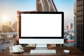 Fototapeta premium Workspace with computer Monitor, Keyboard, blank screen coffee cup smartphone, and tablet on a table or White Screen Isolated in bright office room interior. 
