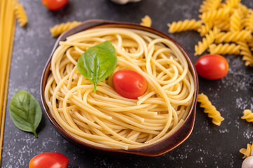 Spaghetti saute in a gray plate with tomatoes and basil