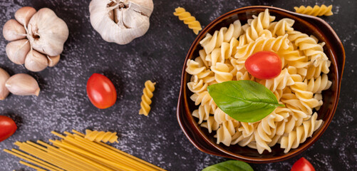 Macaroni sauteed with tomatoes and basil on a gray plate.