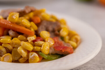 Stir the corn and carrots, put the pork on the plate on the wooden plate.