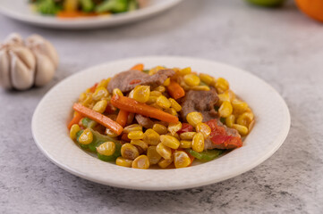 Stir the corn and carrots, put the pork on the plate on the wooden plate.