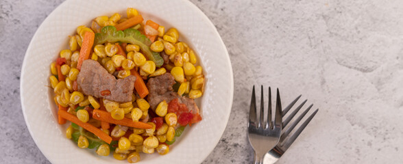 Stir the corn and carrots, put the pork on the plate on the wooden plate.