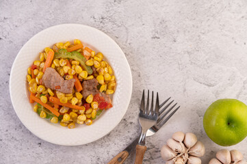 Stir the corn and carrots, put the pork on the plate on the wooden plate.
