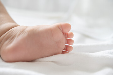 Baby feet in white bed.