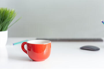 arturo-limon-foto-oficina-fondo-gris-taza-naranja-lápices-teclado-mesa-blanca