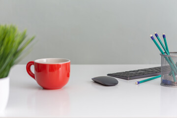arturo-limon-foto-oficina-fondo-gris-taza-naranja-lápices-teclado-mesa-blanca