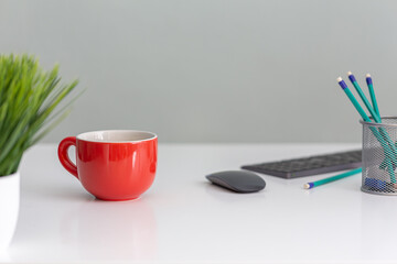 arturo-limon-foto-oficina-fondo-gris-taza-naranja-lápices-teclado-mesa-blanca