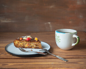 Piece of apple pie on a small white plate and a cup of tea on a wooden background,