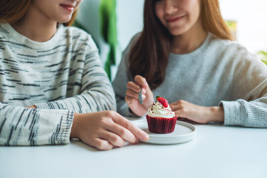 Two women enjoyed eating red velvet cup cake together