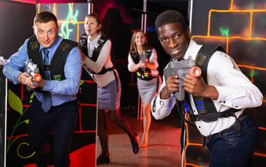 portrait of happy young men and women co-workers having corporate entertainment in laser tag room