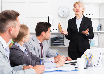 Confident businesswoman explaining to workgroup business plans in office
