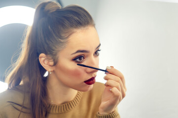 Obraz premium A young beautiful woman makes her own makeup at home .My own makeup artist