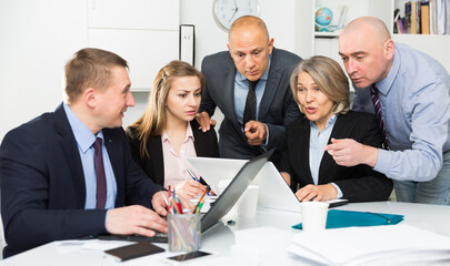 Group of worried business people looking at laptop in modern office